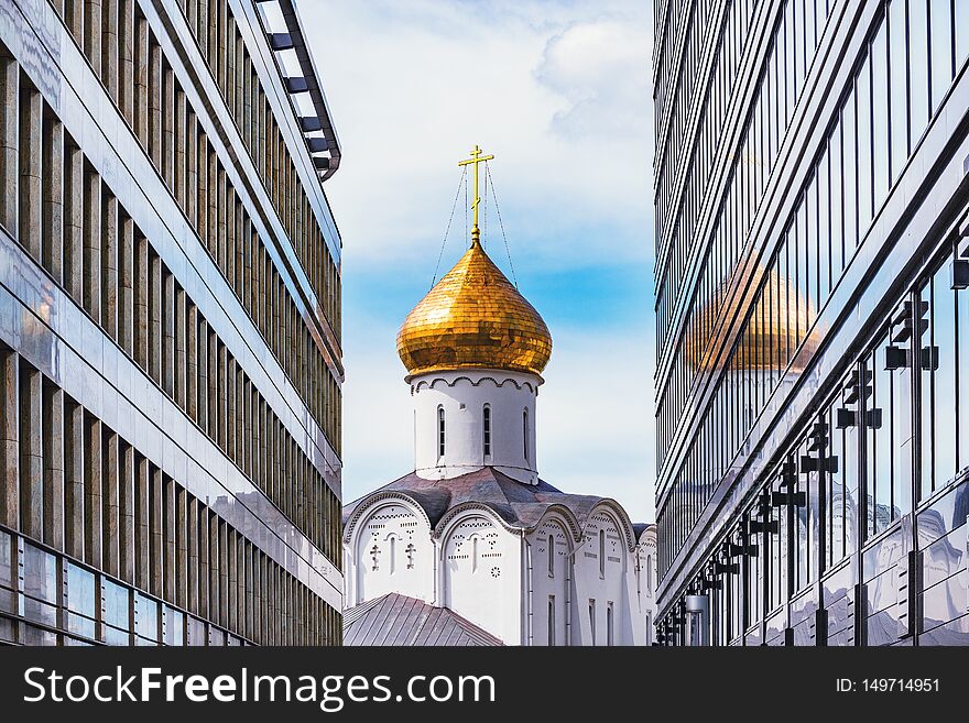 Orthodox church tower between two modern buildings. Moscow