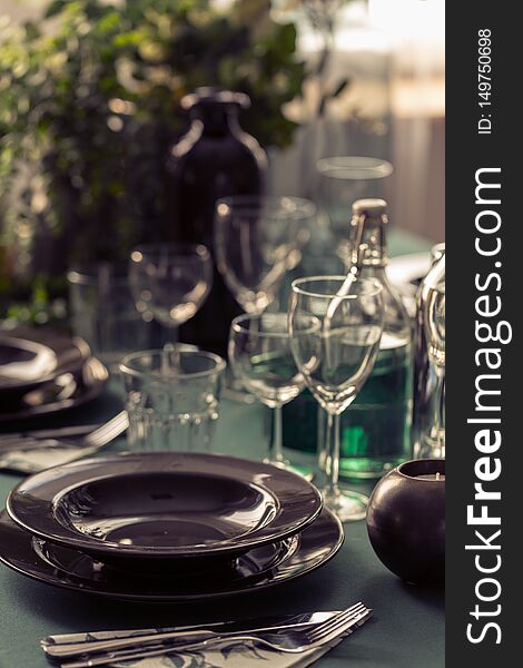 Closeup of black plate on dining room table covered with green tablecloth