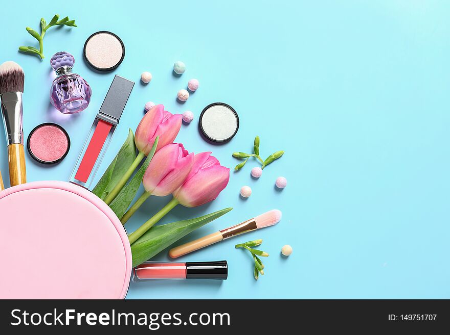 Makeup products, flowers and cosmetic bag on color background, flat lay