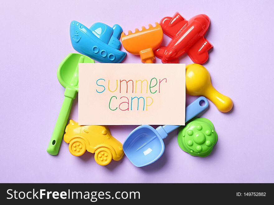 Card with text SUMMER CAMP and different sand molds on color background, flat lay