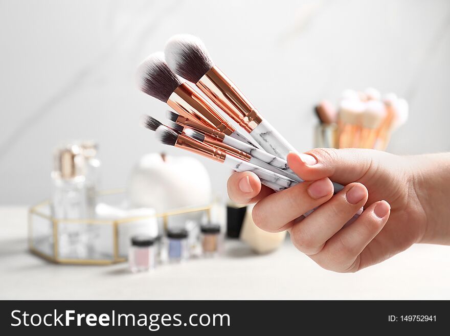Woman holding set of makeup brushes on blurred background, closeup. Woman holding set of makeup brushes on blurred background, closeup