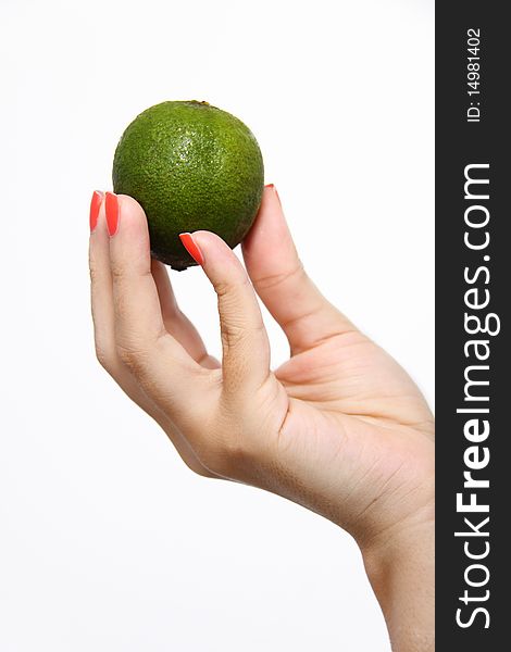 One female hand holding up a green lime. On solid white background. One female hand holding up a green lime. On solid white background.