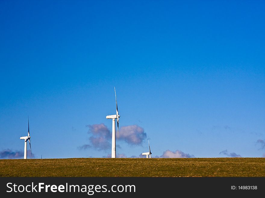 Cornwall's green energy solution are wind turbines on the horizon with a clear blue sky