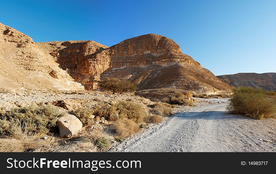 Desert landscape with mountains and road at sunset