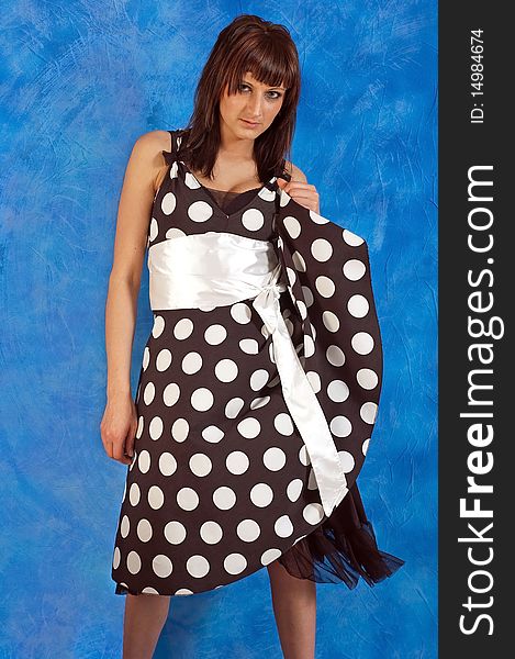 Beautiful girl on the blue mosaic background in a polka-dot dress. Beautiful girl on the blue mosaic background in a polka-dot dress