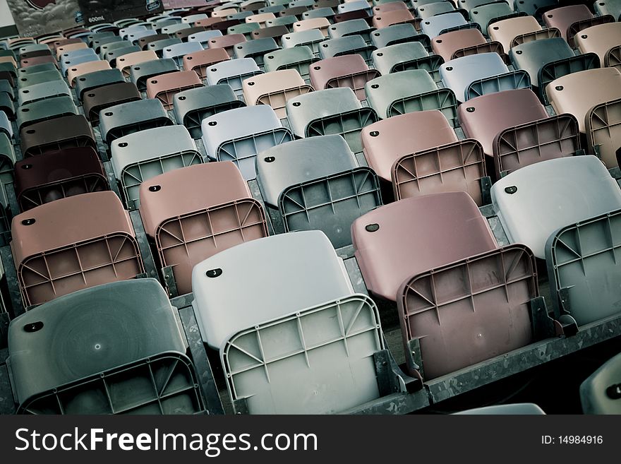 Old colored faded stadium Seats on a row. Old colored faded stadium Seats on a row