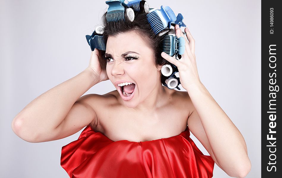 Emotional Girl with hair-curlers on her head. Photo.