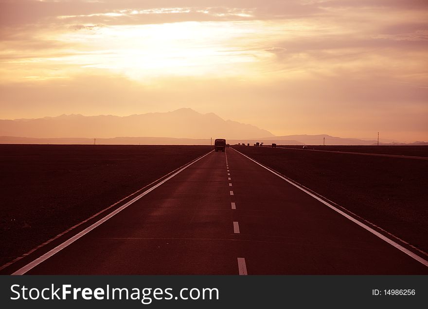 Sunset alsphalt highway and a lonely truck in the wilderness of Urumqi,Sinkiang,West China.