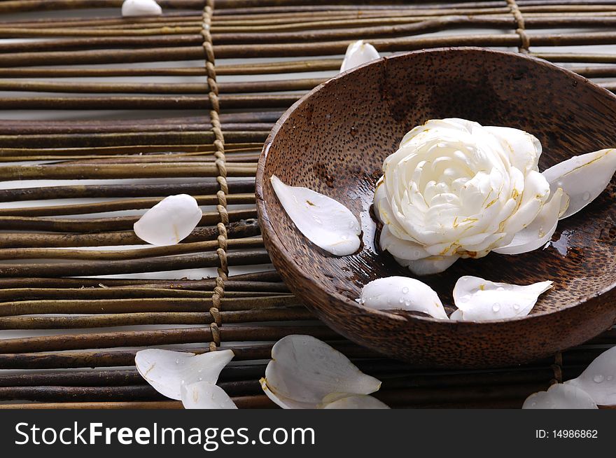 Bowl of camellia blossoms with petal on bamboo mat. Bowl of camellia blossoms with petal on bamboo mat