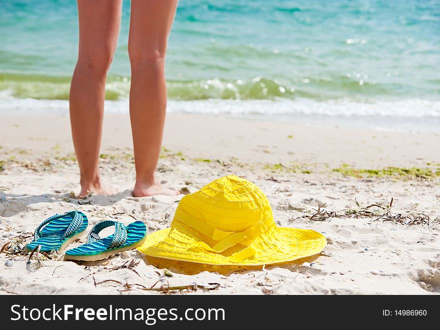 Flip-flop, hat and woman on the beach near sea. Focus on flip-flop. Flip-flop, hat and woman on the beach near sea. Focus on flip-flop