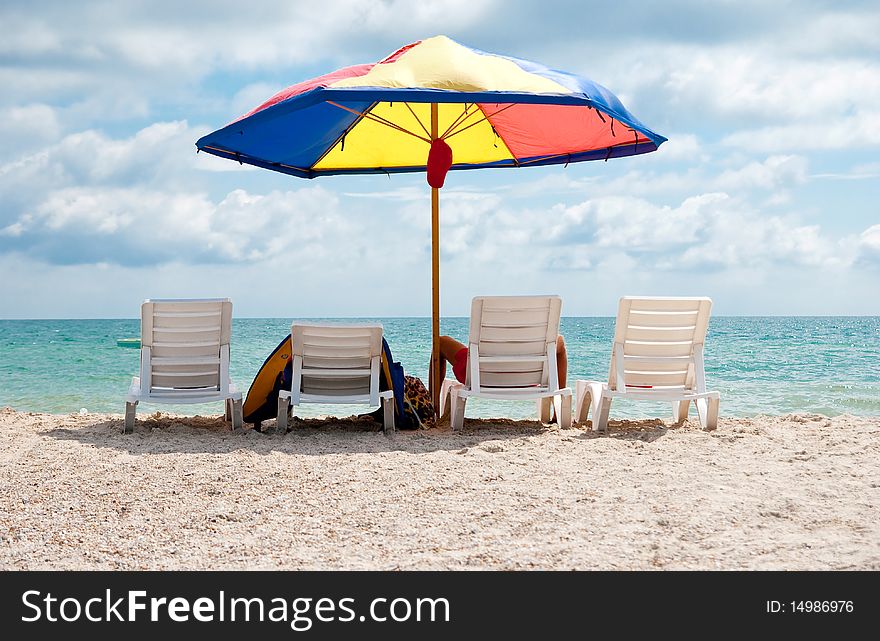 Four white deck chairs and big umbrella on the beach near sea. Four white deck chairs and big umbrella on the beach near sea