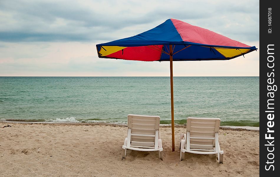 Two beach chairs and umbrella on the sea
