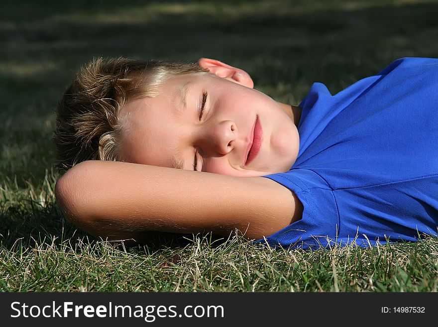 Happy young boy sleeping on the grass