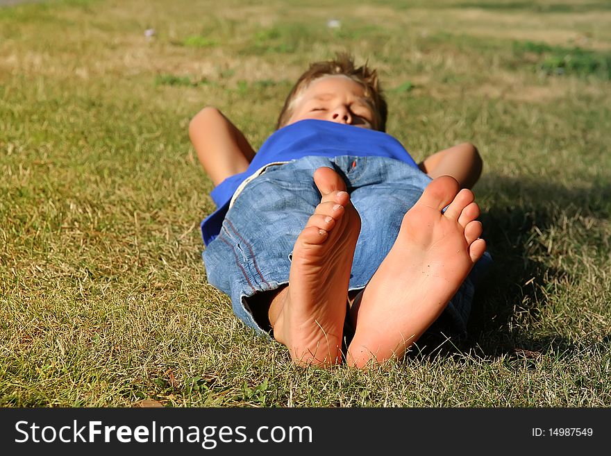 Happy young boy sleeping on the grass