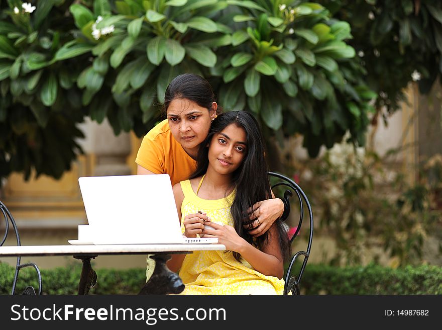 Mother and daughter working on laptop outdoors. Mother and daughter working on laptop outdoors