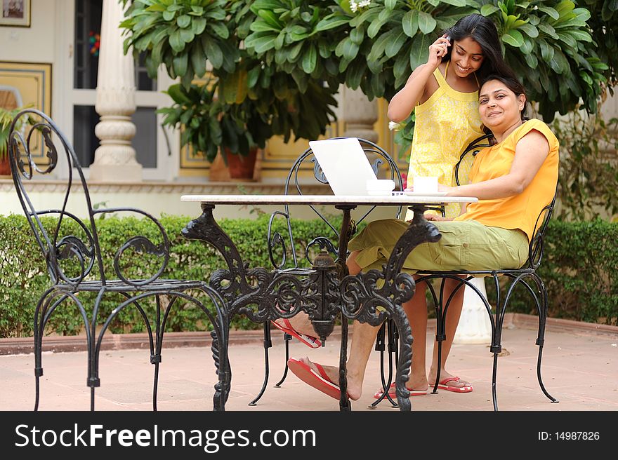 Mother working on computer with daughter in house garden. Mother working on computer with daughter in house garden