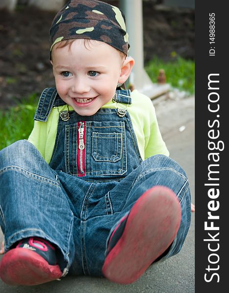 A little boy sits on the ground and smiles. A little boy sits on the ground and smiles