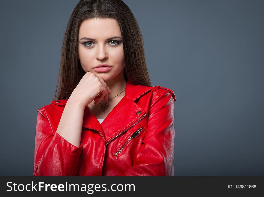 Fashionable style, fashion women`s clothing, color combination. Beautiful brunette girl in white dress and red leather jacket isolated gray background.