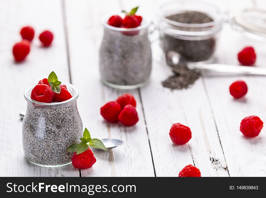 Closeup of served glass jars filled with sweet pudding of chia seeds and garnished with fresh raspberry and mint. Closeup of served glass jars filled with sweet pudding of chia seeds and garnished with fresh raspberry and mint