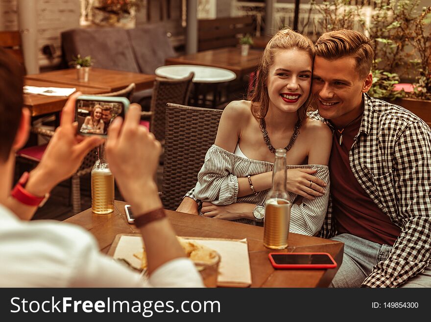 Happy Couple Being Photographed By Their Friend At The Bar.