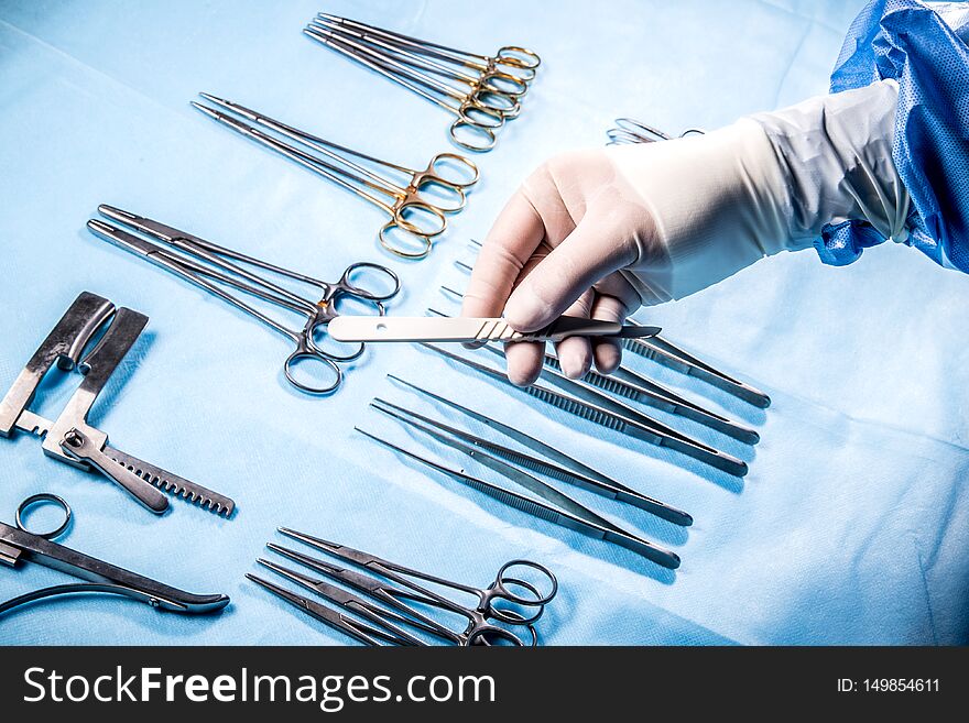 The surgical nurse in sterile gloves gives the surgeon a scalpel during the operation. The surgical nurse in sterile gloves gives the surgeon a scalpel during the operation.