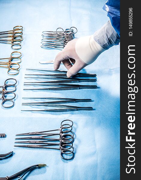 The operation sister takes tweezers to feed him to the surgeon during the operation. The hands of the doctor are wearing sterile gloves.