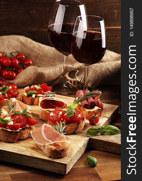 Antipasto various appetizer. Cutting board with prosciutto, salami, cheese, bread and olives on dark wooden background