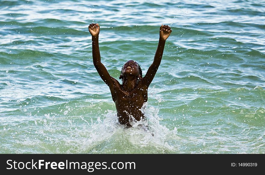 Young bahamian boy raising his arms in such joy after winning his swimming race. Young bahamian boy raising his arms in such joy after winning his swimming race.