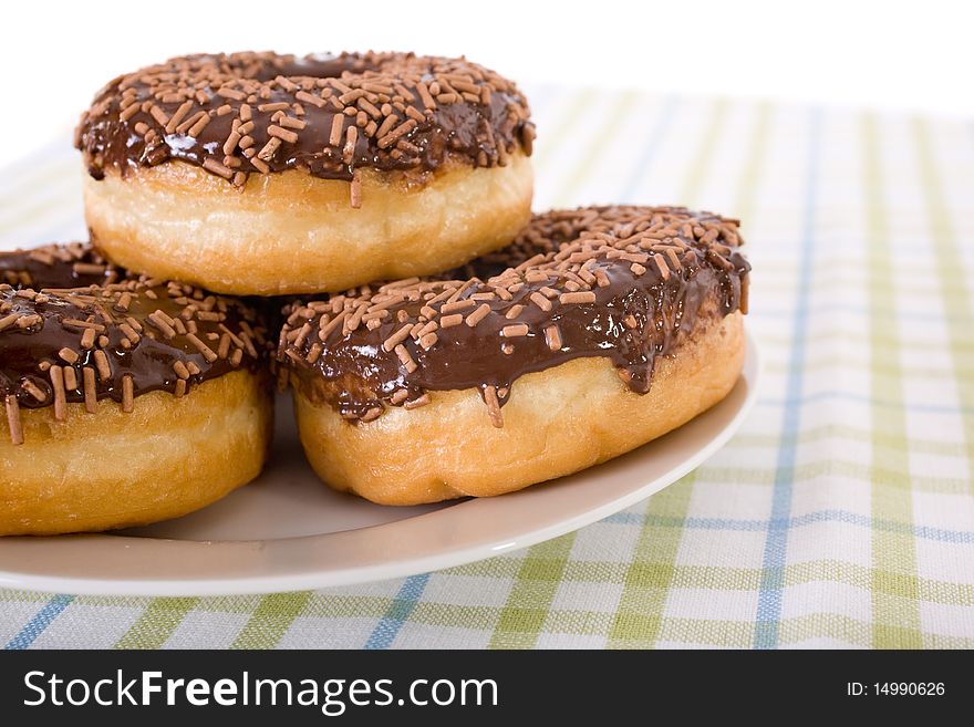 Three donuts on a plate, chocolate glazing