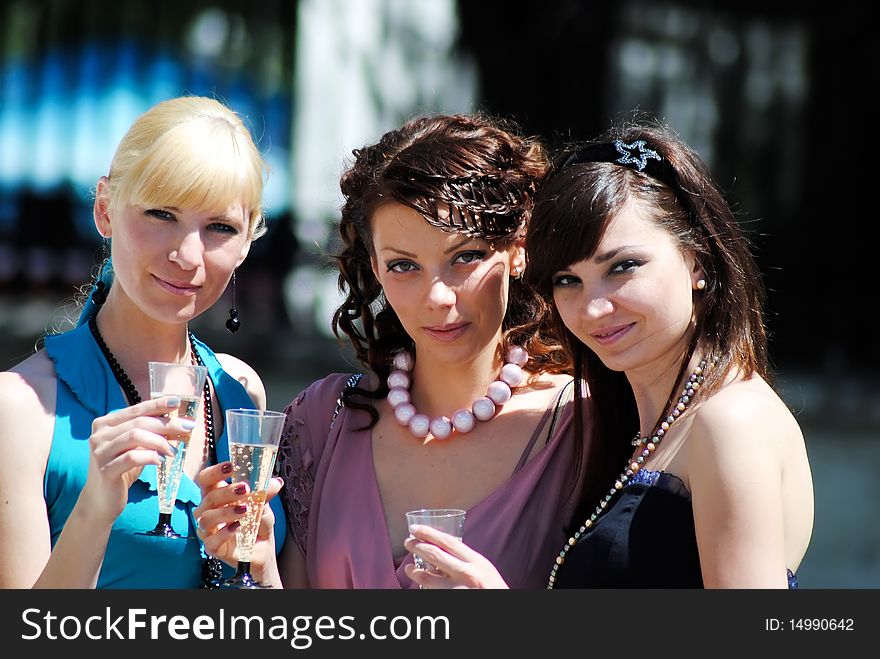 Three young women with glasses of a champagne in hands