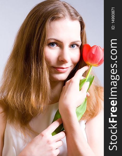 Beautiful young woman holding red tulip