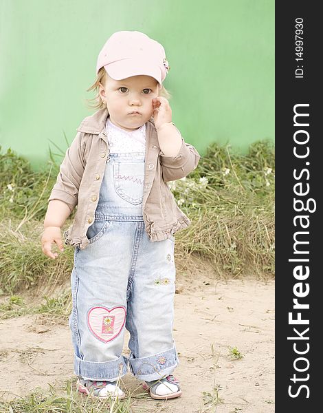 The girl in a cap has reflected, costs on sand in the summer and holds a hand near a cheek. The girl in a cap has reflected, costs on sand in the summer and holds a hand near a cheek