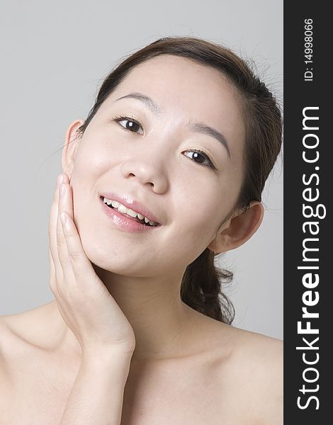 A smiling Asian girl with her hand touching her chin, taken in studio, for skin protection, beauty saloon, cosmetics advertisement use. A smiling Asian girl with her hand touching her chin, taken in studio, for skin protection, beauty saloon, cosmetics advertisement use.