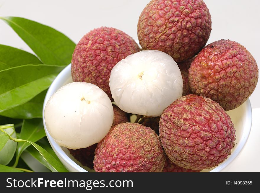 Bowl of Lychees and two peeled with leaf. Bowl of Lychees and two peeled with leaf