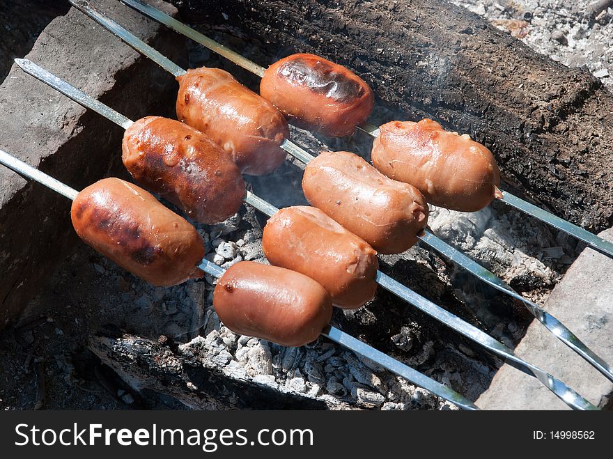 Sausages are prepared on the fire on skewers