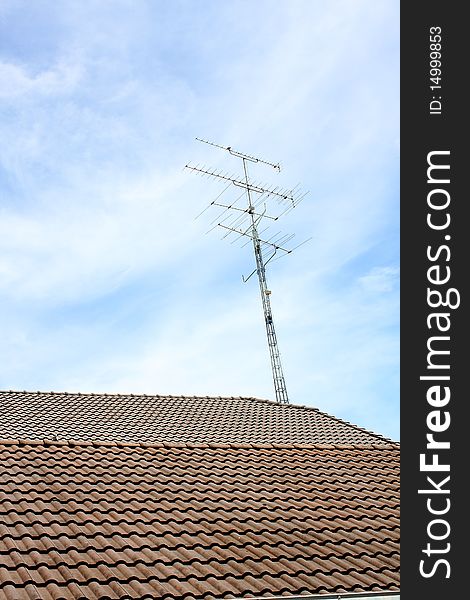 An antenna on the roof with blue cloud sky. An antenna on the roof with blue cloud sky.