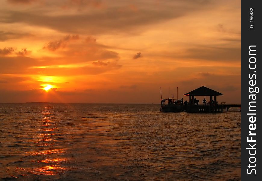 A small boat unloading to a jetty at sunset. A small boat unloading to a jetty at sunset.