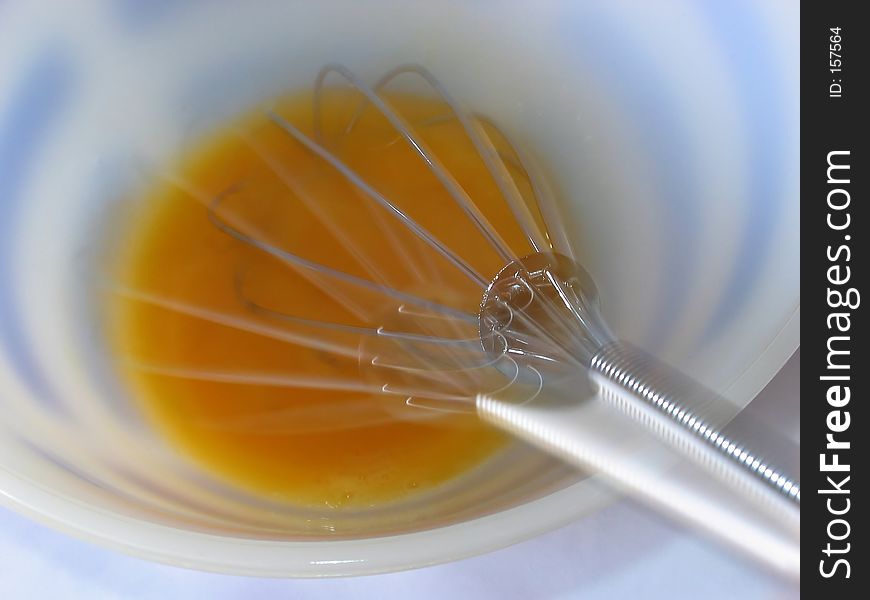 An egg being beaten with a whisk. An egg being beaten with a whisk