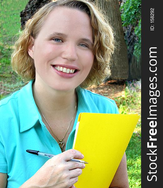 Attractive young woman outdoors with folder and pen