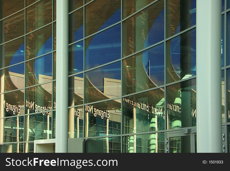 Reflection of the blue sky and part of a building in glasses of a facade creates abstraction