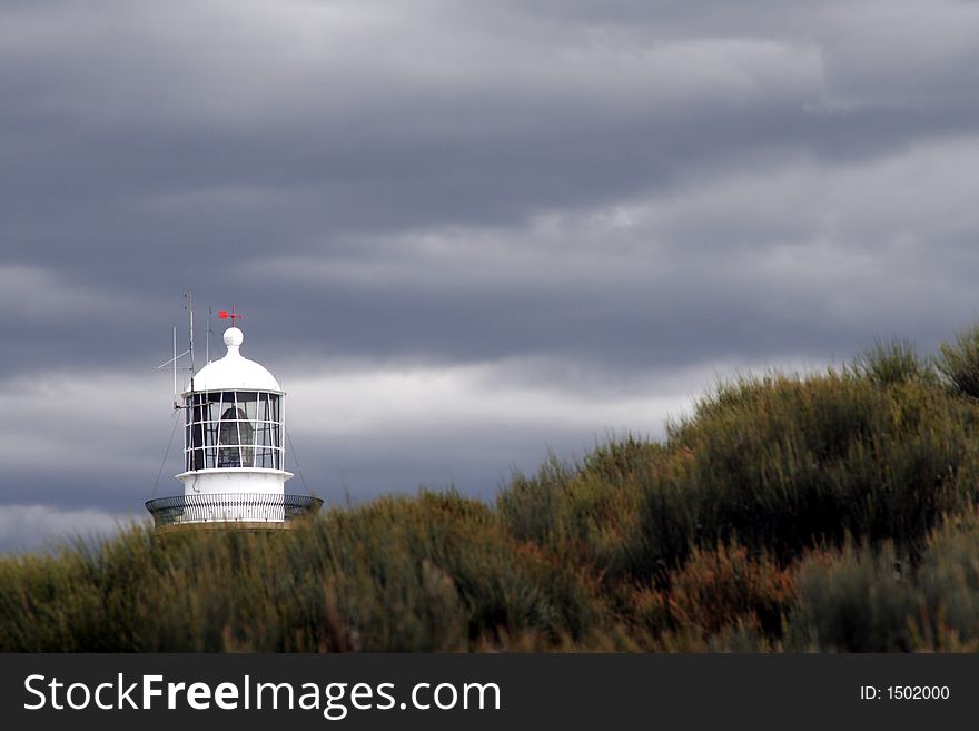 Lighthouse Top Behind A Hill On A Stormy Cloudy Day