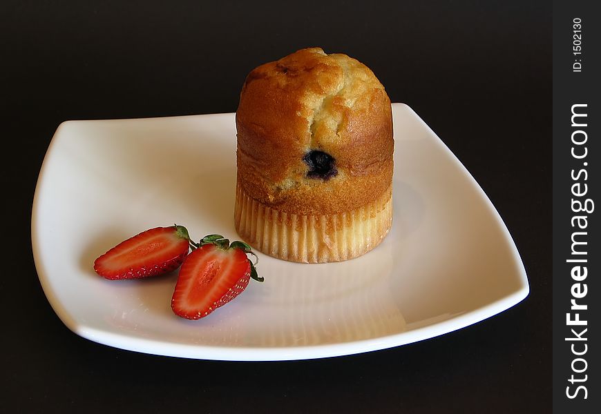 Muffin and strawberry on a white plate. Muffin and strawberry on a white plate