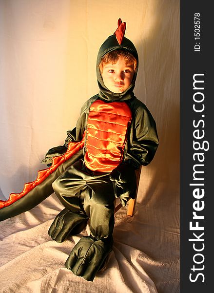 A little boy poses dressed in his green and orange dragon costume. A little boy poses dressed in his green and orange dragon costume.
