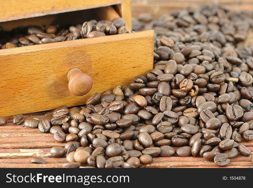 Coffee beans poured out in front of old coffee grinder