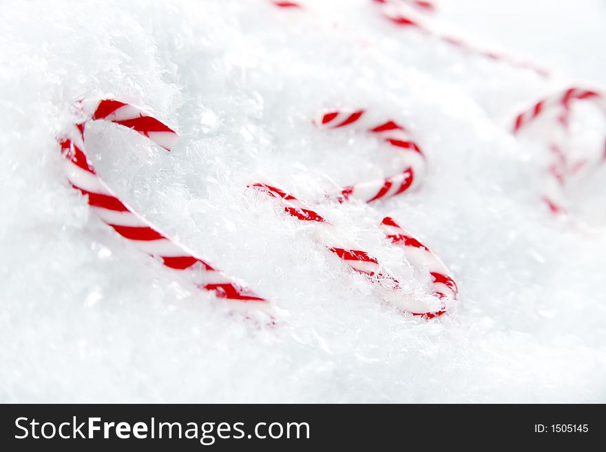 Miniature candy canes in a pile of snowflakes. Miniature candy canes in a pile of snowflakes