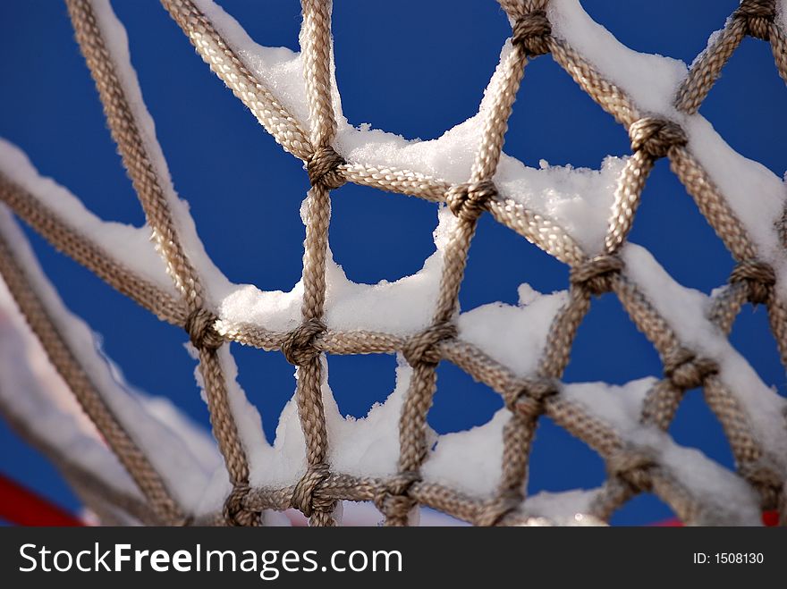 Snow sits on an unused basketball net. Snow sits on an unused basketball net.