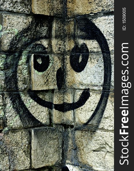 Illegal graffiti - a smiley face spray-painted in a corner of a stone wall. Illegal graffiti - a smiley face spray-painted in a corner of a stone wall.