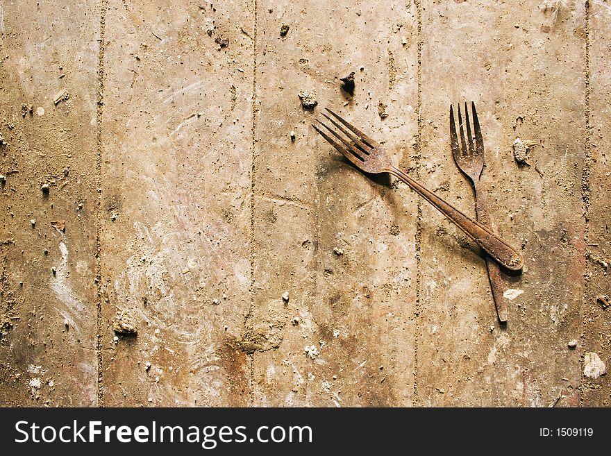A apir of rusty forks on a dirty wooden floor