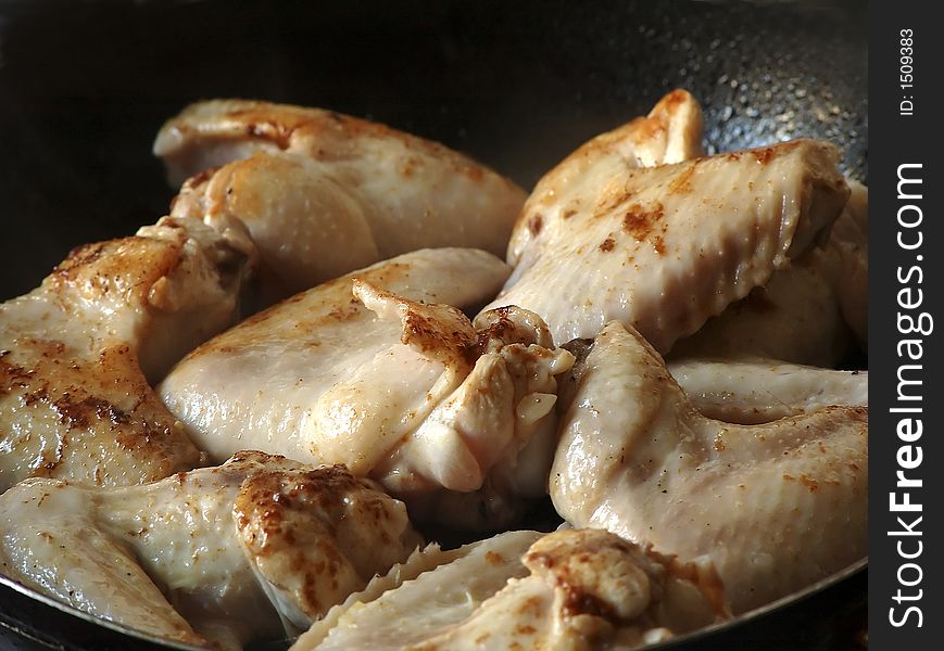 Frying chicken wings on pan