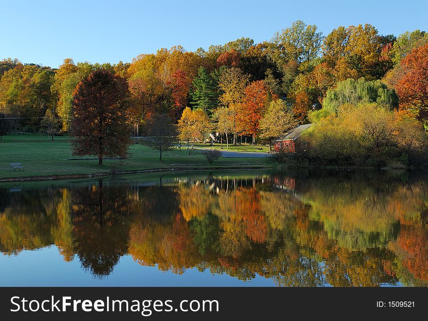 Colorful fall trees and a red building reflected from a lake at a park. Colorful fall trees and a red building reflected from a lake at a park